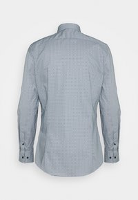 Chemise homme à manches longues boutonnée avec un petit motif géométrique répétitif en nuances de gris et de noir, vue de dos.