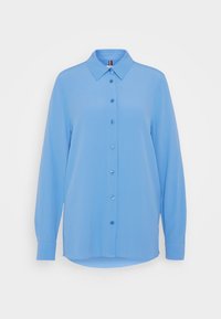 Camicia button-up azzurro chiaro realizzata in tessuto liscio con colletto punta, maniche lunghe e orlo arrotondato; presenta bottoni blu e una leggera lucentezza.