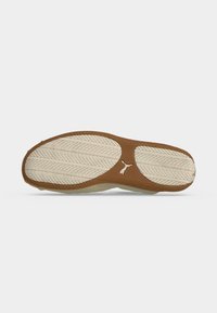 Semelle de chaussure avec une bande de roulement en caoutchouc beige et crème, présentant un motif de feuille et un petit logo Puma au centre.