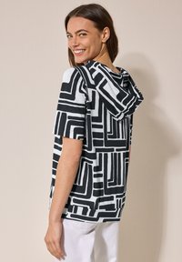 Sudadera negra y blanca con un patrón geométrico, mangas cortas y un corte relajado. Tejido suave y detalle de capucha caída.