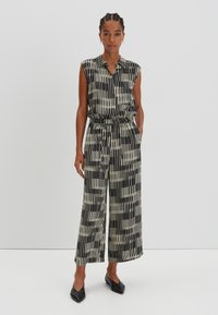 Black and white striped sleeveless jumpsuit with a buttoned collar, elastic waist, and wide legs. Matches with black pointed flats.