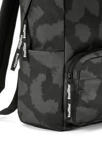 Čierny látkový batoh s textúrovaným vzorom. Detaily zipsu s čiernymi ťahadlami označenými „#nofilter“. Polstrované popruhy pre pohodlie.