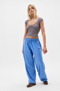 Blue sweatpants with a drawstring waist and side pockets, paired with a fitted striped top featuring short sleeves and a scoop neckline.
