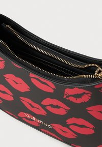 Crna večernja torba s otiskom crvenih usana; sadrži zlatni zatvarač, dva odjeljka i logo "VALENTINO". Glatka tekstura, pravokutni oblik.