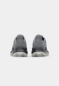 Chaussures de randonnée grises avec une tige respirante, un col rembourré et une semelle noire. Elles présentent un tissu texturé et un motif de semelle à relief pour une meilleure adhérence.