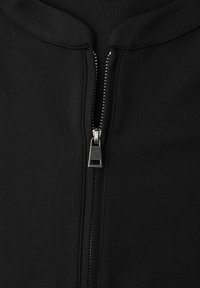 Schwarze Zip-Jacke mit metallischem Reißverschluss und runden Kragen. Hergestellt aus glattem Stoff mit sauberem Finish und ohne sichtbare Muster.