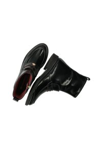 Bottines en cuir noir avec un bout arrondi, une sangle latérale et des accents rouges discrets à l'intérieur et sur la sangle. Semelle plate avec un petit talon.