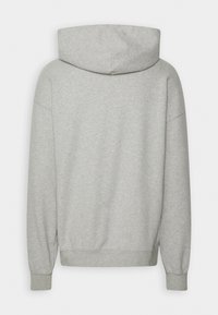 Šedá mikina s kapucí a uvolněným střihem. Měkká, hladká textura, spadlé ramena a žebrované manžety. Bez viditelných log nebo designů.