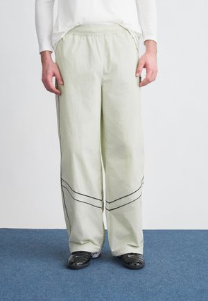 Lichtgroene, loszittende broek met een elastische tailleband; voorzien van zwarte biesjes bij de onderkant en zijzakken.