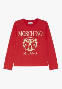 Red long-sleeve t-shirt made of cotton, featuring a gold Moschino logo and ornate design elements printed on the front. Round neckline.
