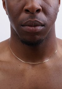 Gold chain necklace on a bare neck, featuring a delicate link design with a smooth surface and shiny finish.