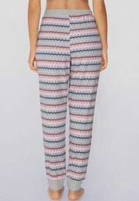 Pantalones de pijama grises con un patrón de zigzag en rayas rosas, azules y rojas, con puños de punto grises y una cintura elástica.