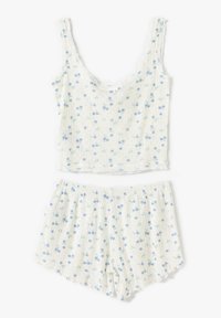 Conjunto de loungewear de algodón que incluye una parte superior sin mangas y pantalones cortos. La tela es blanca con patrones florales azules y una sutil textura acanalada.