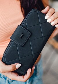 Black quilted wallet made of synthetic material, featuring a zip closure and a rectangular shape with a decorative button accent.