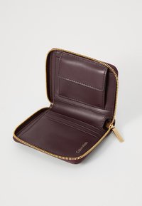 Burgundy leather wallet with gold zipper, interior card slots, smooth texture, and a logo embossed on the side.