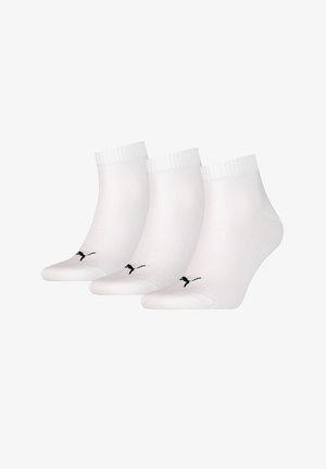 Tres pares de calcetines blancos de tobillo con puños acanalados. Cada calcetín presenta un logo negro en la puntera. Textura suave y material ligero.