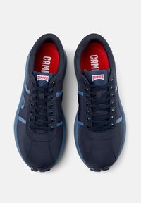 Navy blue athletic shoes with a smooth textile upper, contrasting light blue stripes, and red insoles. Features standard laces and round toe.