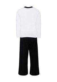 Chemise blanche à manches longues avec un col noir, associée à un pantalon large noir, le tout en tissu doux et léger.