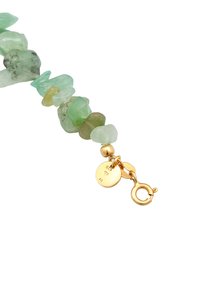 A bracelet made of irregular green gemstones with a gold clasp and circular tags, featuring a textured surface and varying shades of green.