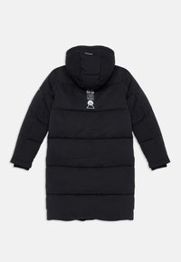Manteau long et noir en duvet avec capuche, présentant des panneaux horizontaux cousus, une étiquette de logo et des poignets en tricot. Tissu lisse et isolant.