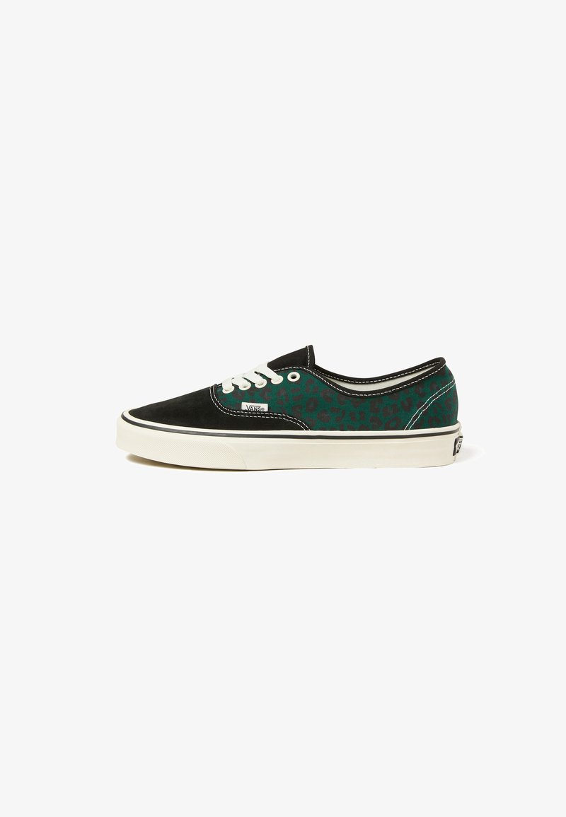 Schwarze und grüne Vans Sneaker mit Leopardenmuster, weißen Schnürsenkeln und weißer Gummisohle auf einem weißen Hintergrund, Seitenansicht.