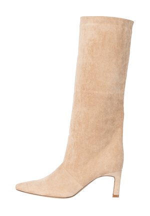 Bota de mujer alta hasta la rodilla de ante beige, con punta afilada y tacón de bloque de altura media, mostrada de perfil sobre fondo blanco.