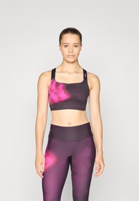 Sporta krūšturis un legingi komplekts tumši purpura krāsā ar rozā tie-dye akcentiem; gluda tekstūra, kvadrātveida dekoltē un platas siksnas atbalstam.
