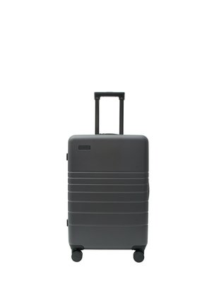 Dunkelgrauer Hartschalenkoffer mit ausgezogenem Teleskopgriff und vier Rollen, stehend auf weißem Hintergrund.