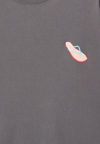 Grå T-shirt lavet af bomuld, med et lille pink flip-flop design med blå stropper broderet på forsiden. Enkel og afslappet stil.