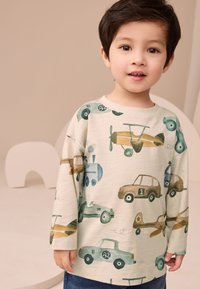 Jasnobeżowa koszulka z długim rękawem z kolorowymi wzorami pojazdów, w tym samochodów i samolotów, o miękkiej fakturze i luźnym kroju.