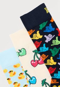 Τρεις πολύχρωμες κάλτσες με σχέδια: κίτρινοι λαστιχένιοι πάπιες σε ανοιχτό μπλε, κεράσια και μήλα σε κρεμ, και πολύχρωμα χέρια σάκα σε ναυτικό μπλε.
