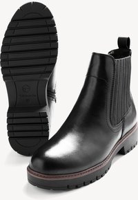 Botas de tobillo de cuero negro con un acabado suave, paneles laterales elásticos y una suela de goma resistente. Presentan un tacón bajo y costuras detalladas.