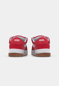 O pereche de adidași roșii Vans cu talpă intermediară albă și talpă exterioară din cauciuc, văzuți din spate arătând logo-ul Vans pe călcâi.