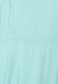 Tecido azul claro com um padrão texturizado subtil, apresentando pequenos pontos em relevo. Acabamento suave com costuras visíveis.