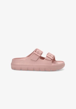 Zueco de plataforma rosa hecho de goma, con dos correas ajustables con hebilla, punta abierta y suela texturizada para agarre.