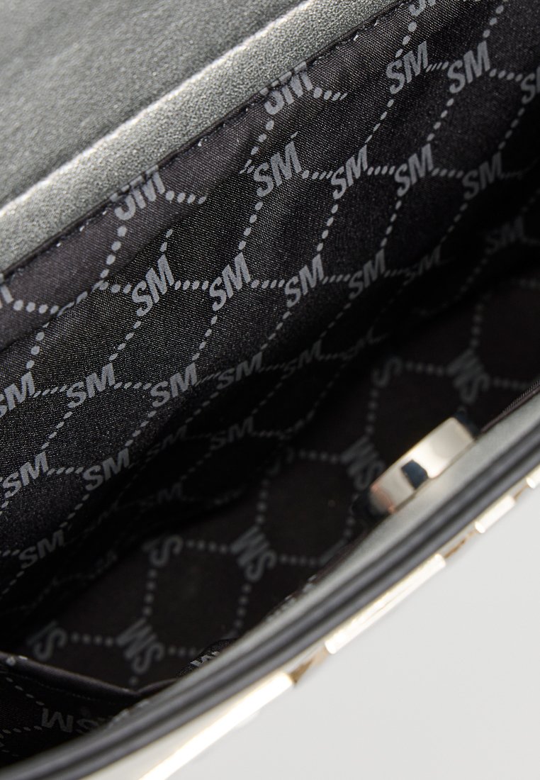 Intérieur de sac à main noir avec une texture lisse, doublure à motif hexagonal avec le logo "SM" et détails en métal.
