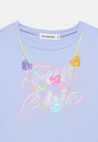 Ανοιχτό μπλε μπλουζάκι με εκτύπωση «Fun But Chic» σε ζωντανά χρώματα. Διακοσμημένο με πολύχρωμες καρδιές από παγιέτες και στρογγυλή λαιμόκοψη.