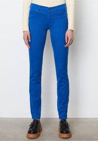 Jeans elásticos azules con un ajuste Slim, que cuentan con cinco bolsillos, cierre de botón y presillas para cinturón. Textura de tela suave y color vibrante.