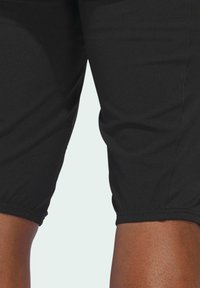 Black athletic capris made from stretch fabric, featuring a fitted design and elasticated cuffs at the ankles. Smooth, matte texture.