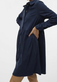 Mörkblå skjortklänning i mjukt, texturerat material med knäppning fram, krage, långa ärmar och design med rynkad midja.