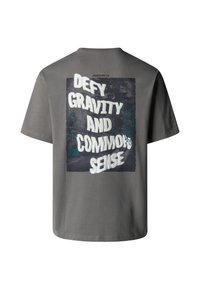 Šedé bavlněné tričko s grafickým designem na zadní straně, na němž je v tučných bílých písmenech napsáno "VYHÝBEJ SE GRAVITACI A ZDRAVÉMU ROZUMU".