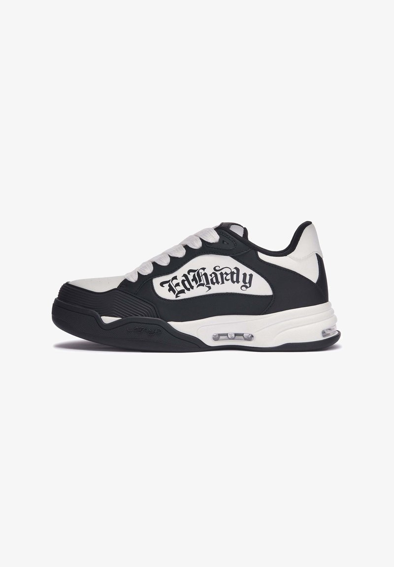 Schwarz-weißer Sneaker mit runder Zehenpartie, strukturierten Gummisohle, auffälliger Markenkennzeichnung in gotischer Schrift und Schnürverschluss.