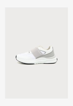 Baskets Calvin Klein blanches et grises avec une semelle épaisse et une large sangle élastique sur le médio-pied, sur un fond uni clair.