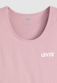 Világos rózsaszín pamut póló, kerek nyakkal és fehér "LEVI'S" logóval a bal mellen. Puhább anyag finom textúrával.