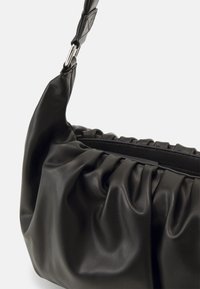 Sac à main en cuir noir avec un design plissé, doté d'une texture lisse et d'une bandoulière amovible avec une quincaillerie et des accents argentés.