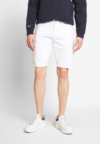 Shorts bianchi in cotone con taglio dritto, dotati di tasche frontali e zip con bottone. Abbinati a sneakers bianche con dettagli blu navy.