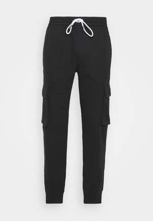 Pantalon cargo jogger noir avec taille élastique, cordon blanc, poches latérales à rabat et chevilles resserrées sur fond blanc.