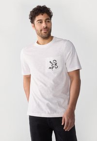 White cotton t-shirt with short sleeves, featuring a pocket adorned with black floral embroidery on the left side.