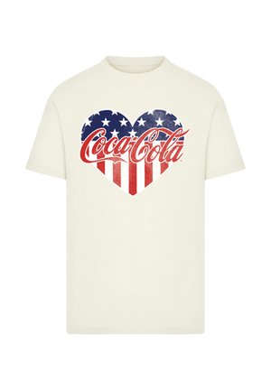 Cream-colored t-shirt featuring a heart design with red and white stripes and blue stars, prominently displaying the Coca-Cola logo.