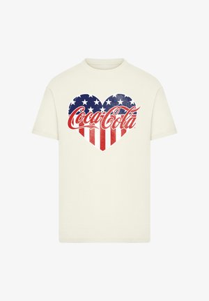 Cream-colored t-shirt featuring a heart design with red and white stripes and blue stars, prominently displaying the Coca-Cola logo.